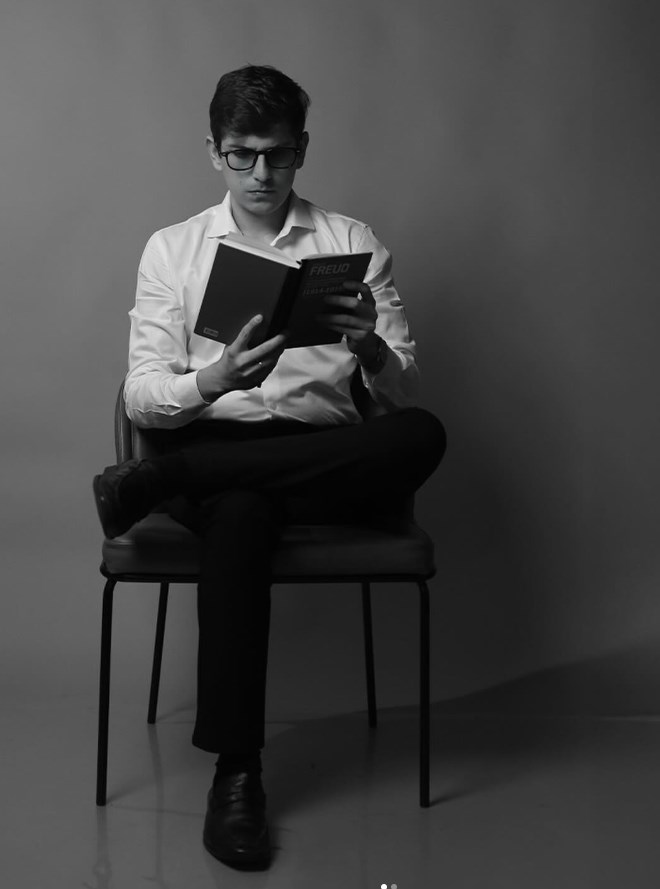 Luiz Felipe Soares, psicólogo, sentado lendo um livro de Freud